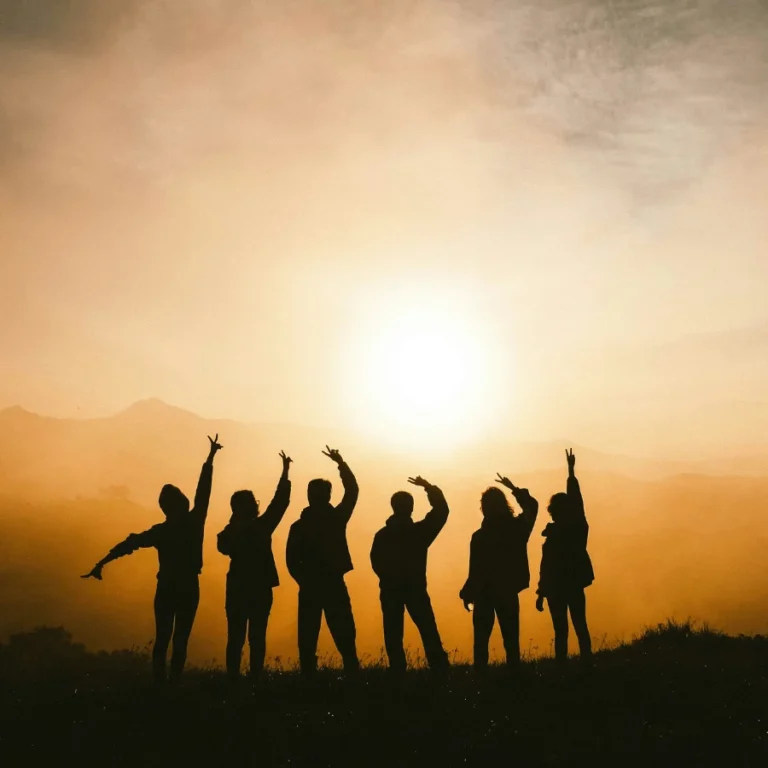 Un groupe de personne en contre-jour face à un coucher de soleil