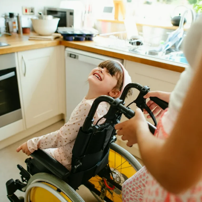 une enfant en fauteuil roulant regarde sa mère en souriant