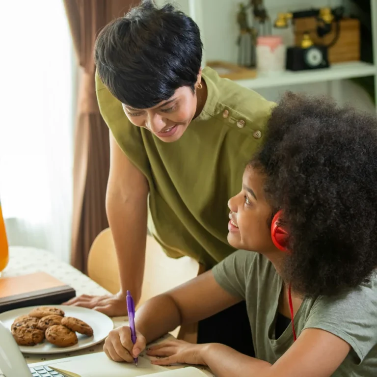 Mère qui partage un goûter avec sa fille qui fait ses devoirs