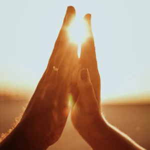 Deux mains se touchant devant un coucher de soleil