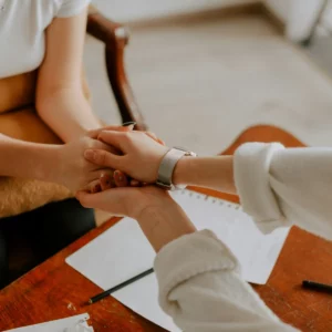 Une femme soutenant une autre femme lors d'un moment difficile en lui tenant les mains