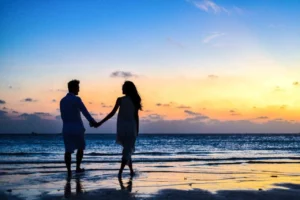 un couple face au coucher de soleil sur une plage
