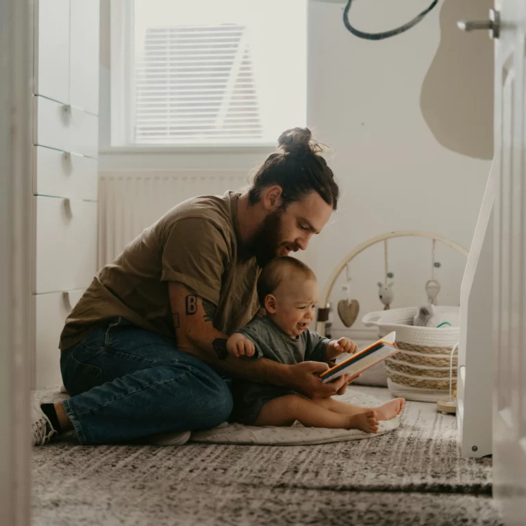 un père en train de lire un livre à son bébé